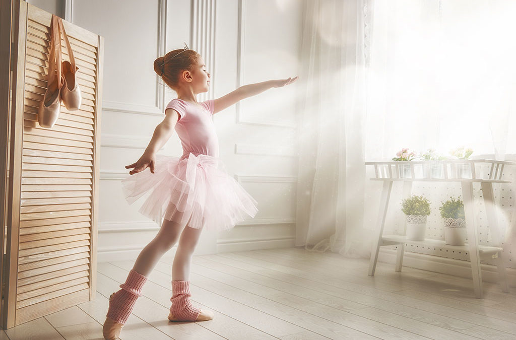cute little girl looking out window dreams of becoming a ballerina